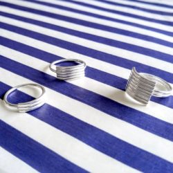 Silver Stripes Ring collection by Essemgé - 3 variations of silver ring on a white and blue striped background