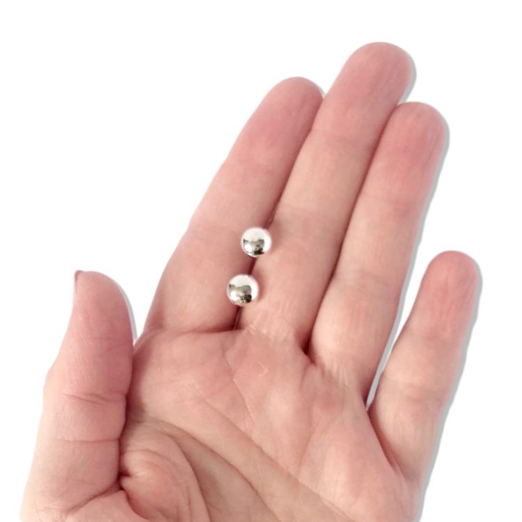 silver round pebble stud earrings on palm of hand against white background