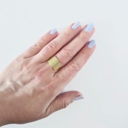 Gold Striped Ribbed Textured Ring - shown worn on middle finger of left hand - against white background