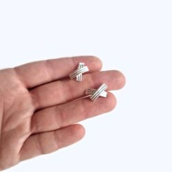 XX shiny silver stud earrings - held in hand - on white background