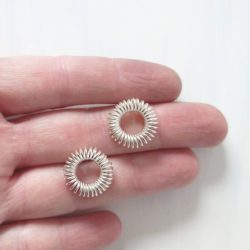 Silver round coil stud earrings - on hand for scale