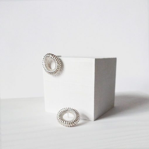 Silver round coil stud earrings - on white cube display