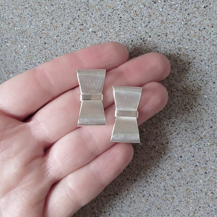Silver Bowknot Stud Earrings - shown on palm of hand for scale