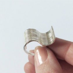 Silver Wave Ring - held between index and thumb - on white background