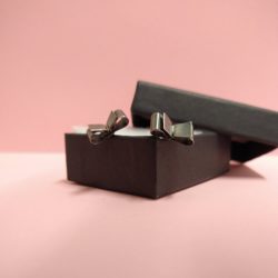 Black Silver Bowknot Stud Earrings by Essemgé - oxidised sterling silver 925 - in a box against blush pink background
