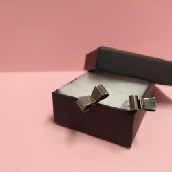 Black Silver Bowknot Stud Earrings by Essemgé - oxidised sterling silver 925 - in a box against blush pink background