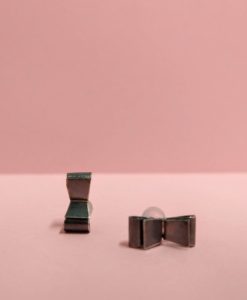Black Silver Bowknot Stud Earrings by Essemgé - oxidised sterling silver 925 - one upright one sideways - against blush pink background
