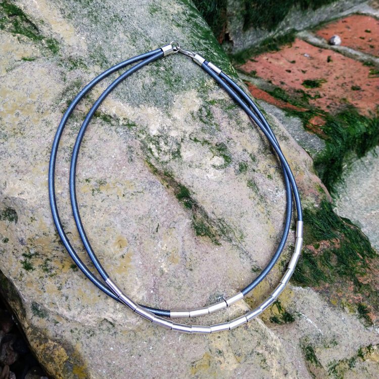 Silver Drape Multirow Necklace by Essemgé - dark grey necklace on rock