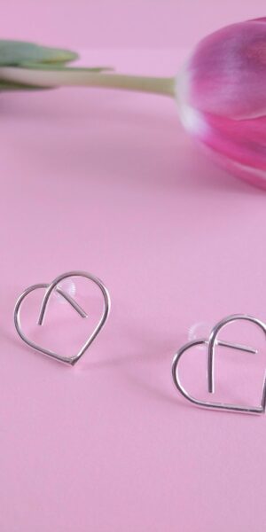 Midi Silver Heart Studs by Essemgé - silver stud earrings in heart shape , on pink background