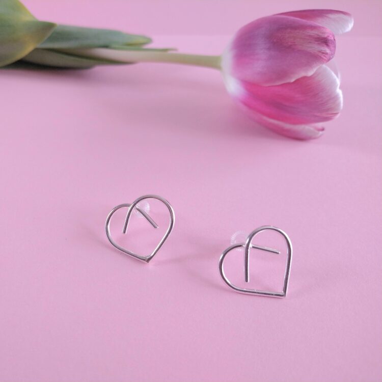 Midi Silver Heart Studs by Essemgé - silver stud earrings in heart shape , on pink background