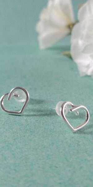 Mini Silver Heart Studs by Essemgé - silver stud earrings in heart shape , on green background