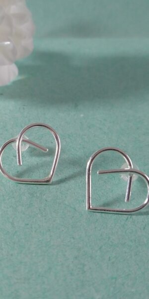 Midi Silver Heart Studs by Essemgé - silver stud earrings in heart shape , on green background