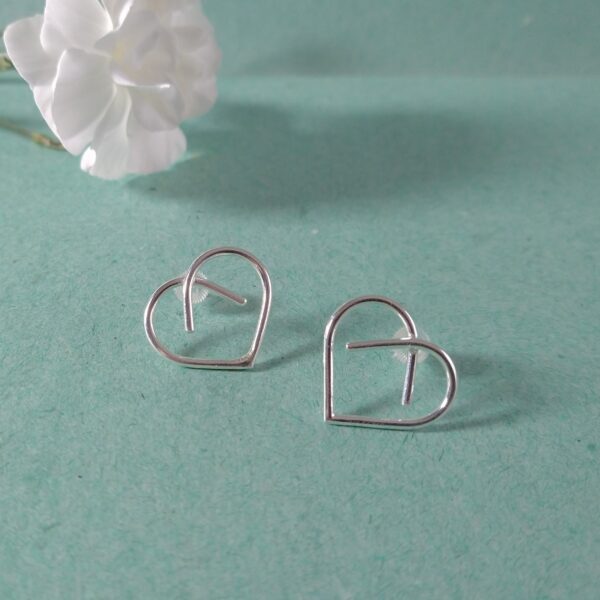 Midi Silver Heart Studs by Essemgé - silver stud earrings in heart shape , on green background