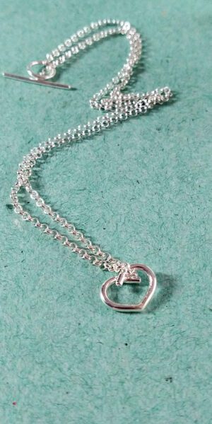 Mini Silver Heart Pendant Necklace by Essemgé - on green background