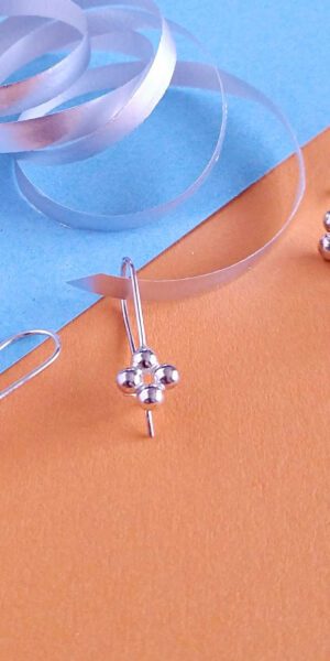 Quatrefoil Caviar earrings collection by Essemgé - silver earrings on sapphire blue and fire opal orange background