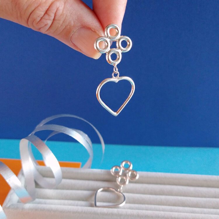 Quatrefoil Heart Dangle Earrings by Essemgé - silver earrings show between fingers for scale
