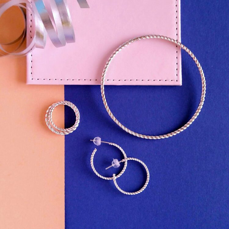 Twisted Rope jewellery collection by Essemgé, including hoops, bangle and a set of rings - silver jewellery on colourful background