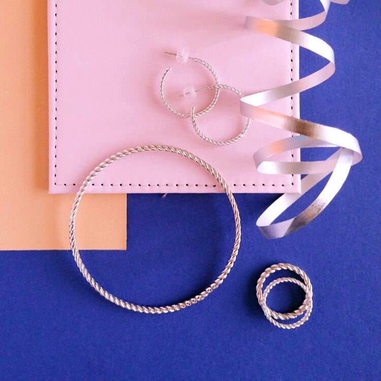 Twisted Rope jewellery collection by Essemgé, including hoops, bangle and a set of rings - silver jewellery on colourful background